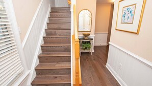 Eine Holztreppe mit weißen Geländern, einem Spiegel und einem gerahmten Kunstwerk an der Wand.