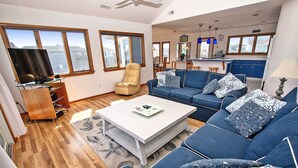 A living room with a sofa, armchair, and a coffee table. There is a television on a stand and a window with a view of the outside. - Semi-Oceanfront, Private Pool, Hot Tub, Close to Beach Access, GF2, Touch of Grey (Duck)