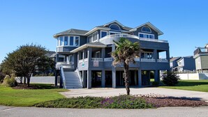A multi-story residential building with a balcony, a flag, and a well-maintained lawn. - Semi-Oceanfront, Private Pool, Hot Tub, Close to Beach Access, GF2, Touch of Grey (Duck)