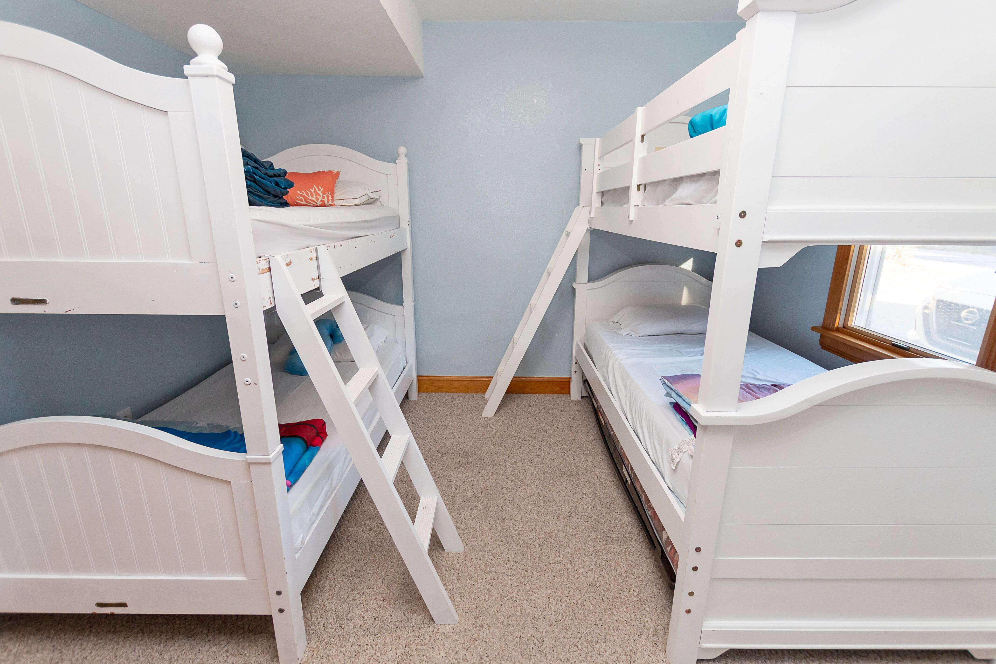 A room with bunk beds, a ladder, and a window.