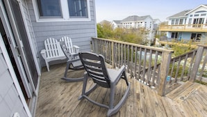 Eine Holzterrasse mit zwei Schaukelstühlen und einem weißen Adirondack-Stuhl.