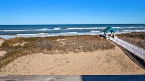 A beach with a wooden boardwalk leading to a blue-roofed structure.