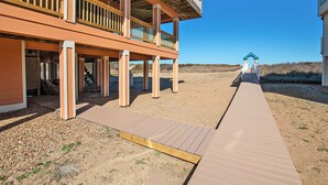 A beachfront property with a wooden deck leading to a covered area with a balcony.
