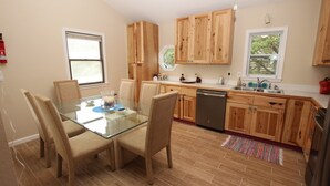 Una cucina moderna con mobili in legno, un tavolo da pranzo in vetro e una lavastoviglie.
