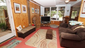 Un soggiorno accogliente con pareti in legno, un grande televisore, una poltrona e un divanetto, e un tappeto decorato.