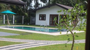 A swimming pool area with a house in the background. - JAS Residence Pool Villa (Divulapitiya)