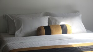 A bed with white bedding and a single decorative pillow with black and gold stripes. - JAS Residence Pool Villa (Divulapitiya)