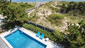 A swimming pool with blue water, surrounded by greenery and a wooden deck.