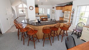A spacious kitchen with a large island, wooden chairs, and a dining table.