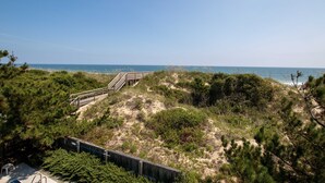 A beach with a wooden walkway leading to the shore, surrounded by dense vegetation.