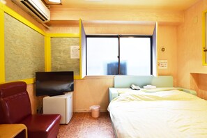 A compact hotel room with a bed, a small desk with a television, a red chair, and a window with a view of a building. - Hotel SAN MARCO (Tokyo)