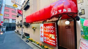 Un hôtel avec un auvent rouge et une enseigne indiquant les tarifs des chambres.