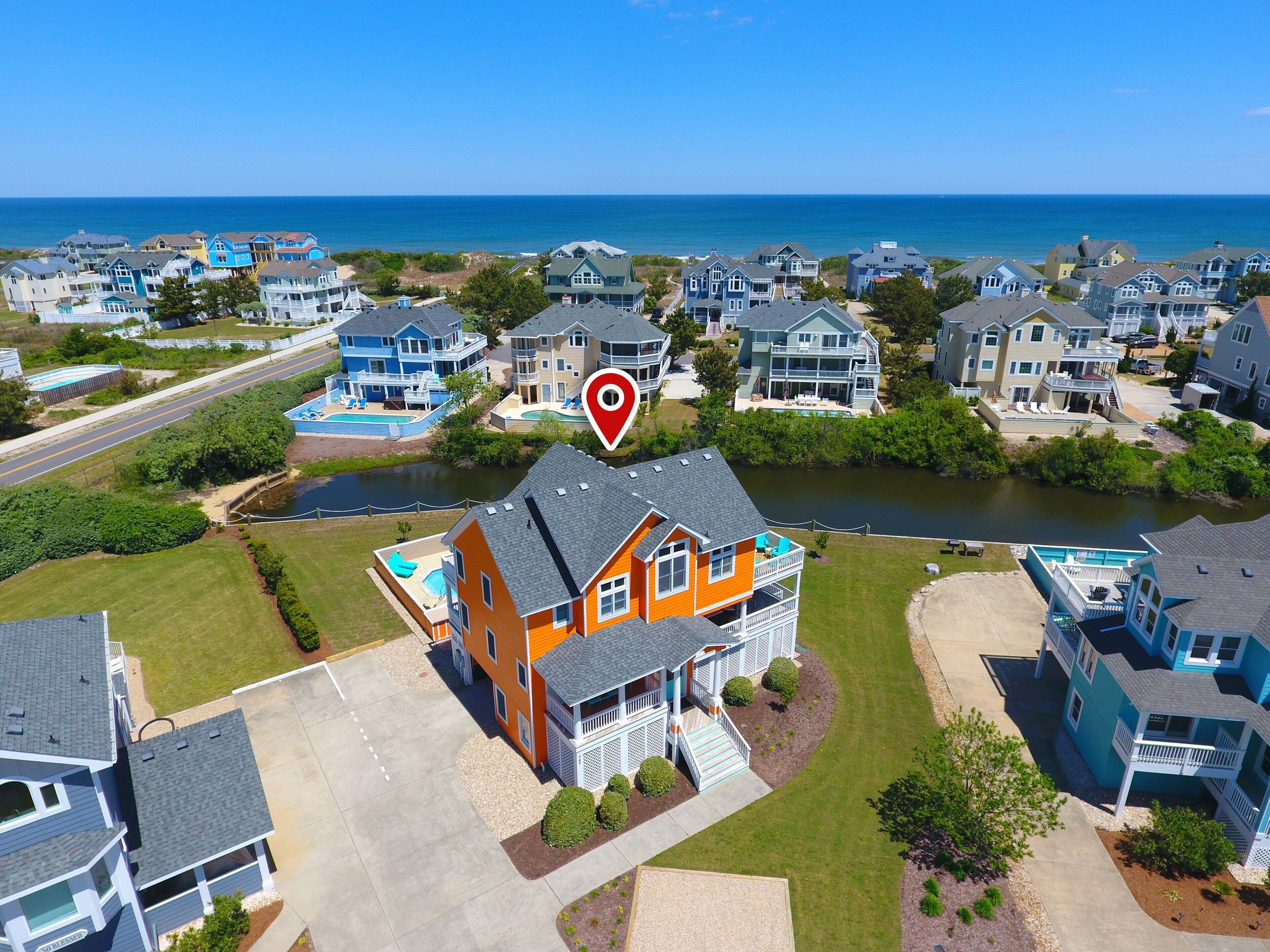 An aerial view of a residential area with houses, a river, and a beach.