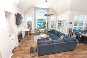 A spacious living area with a large gray sofa, a dining table, and a fireplace.