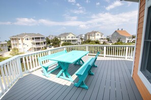 A wooden deck with a turquoise picnic table and benches, surrounded by a white railing. - Oceanside, Hot Tub, Private Pool, Community Amenities, BU3, Tangerine Dream (Corolla)