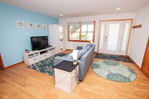 A living room with a TV, sofa, and a patterned rug.