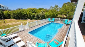 A rectangular swimming pool with a wooden deck, surrounded by a white fence and blue chairs. - Semi-Oceanfront, Private Pool, H Tub, Pool Table, WL864, Porch Coffee Paradise (Corolla)