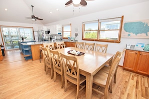 A spacious kitchen with a large island, wooden chairs, and a dining table.