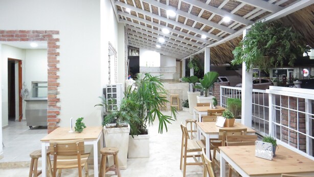 A spacious indoor area with multiple wooden tables and chairs, a brick wall, and a ceiling with wooden beams and recessed lighting. - Bohio Punta Cana (Punta Cana)