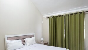 A neatly made bed with white linens in a room with green curtains and a white nightstand. - Bohio Punta Cana (Punta Cana)