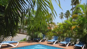 A swimming pool with blue tiles, surrounded by palm trees and lounge chairs. - Bohio Punta Cana (Punta Cana)