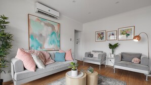 A modern living room with a grey sofa, two side tables, a coffee table, and a large abstract painting. - Heart of Ormond Apartment  by Ready Set Host (Ormond)