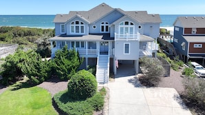 A two-story house with a balcony, a front porch, and a view of the ocean. - OCEANFRONT, 8 BRs, Rec Rm, Pool, H Tub, Media Rm, Ocean Views, OS24C, Flying Cloud II (Corolla)