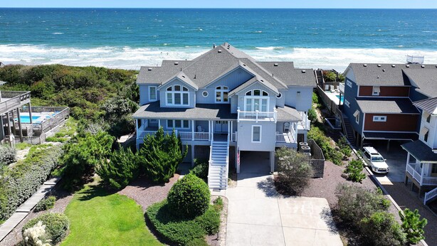 A large two-story house with a balcony, located near a beach with ocean views. - OCEANFRONT, 8 BRs, Rec Rm, Pool, H Tub, Media Rm, Ocean Views, OS24C, Flying Cloud II (Corolla)