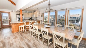 Une cuisine spacieuse dotée d’un îlot central en bois, de meubles blancs et de grandes fenêtres offrant une vue sur le quartier.