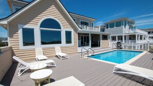 A poolside area with lounge chairs, a pool, and a building with a balcony. - OCEANFRONT, Ocean Views, Private Pool, Rec Room, 230, Long Weekends (Corolla)