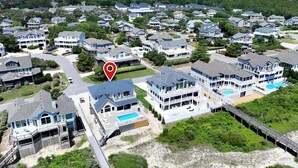 A coastal residential area with houses featuring balconies, a swimming pool, and a lighthouse in the background. - OCEANFRONT, Ocean Views, Private Pool, Rec Room, 230, Long Weekends (Corolla)