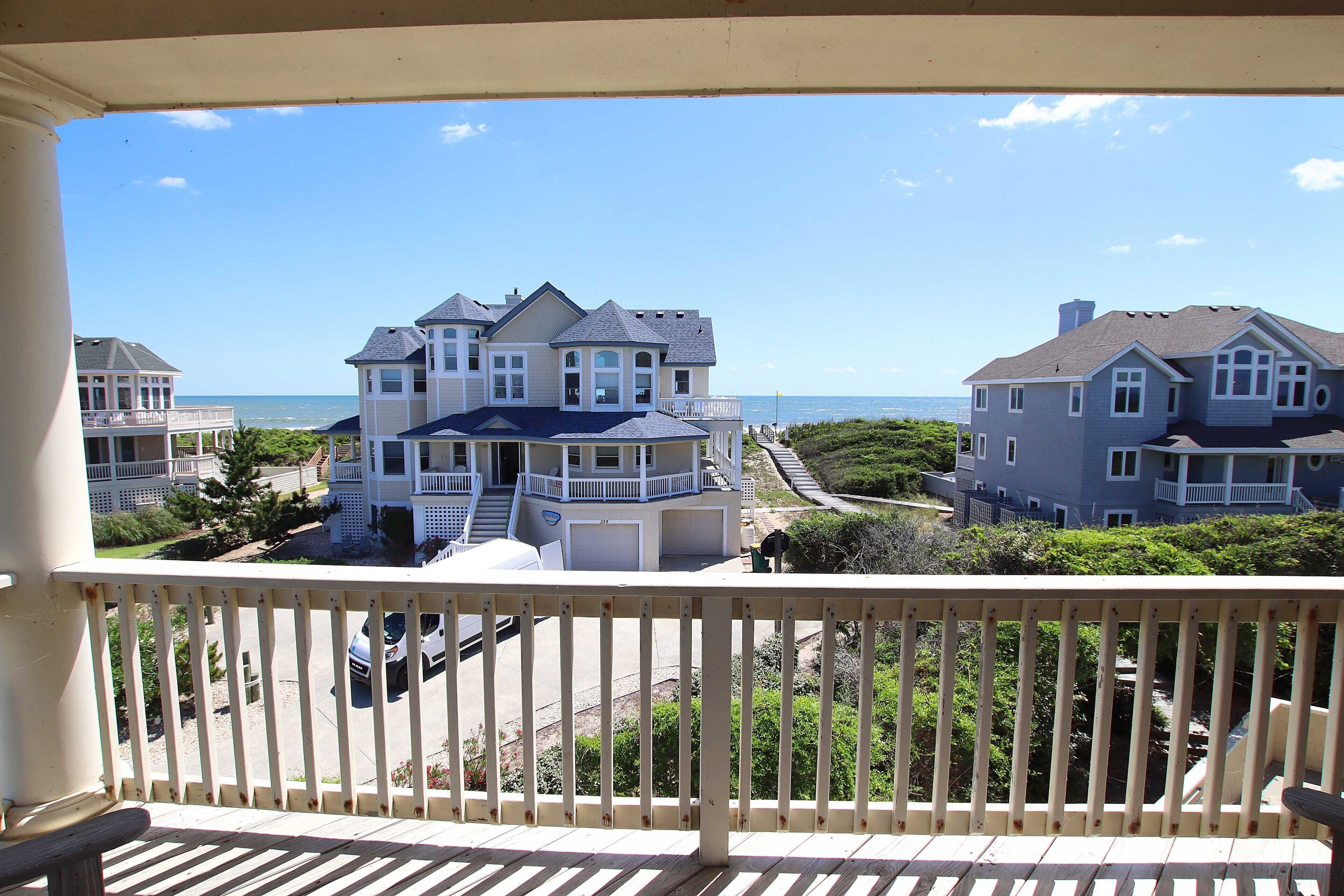 A large, multi-story house with a balcony, located near a body of water.