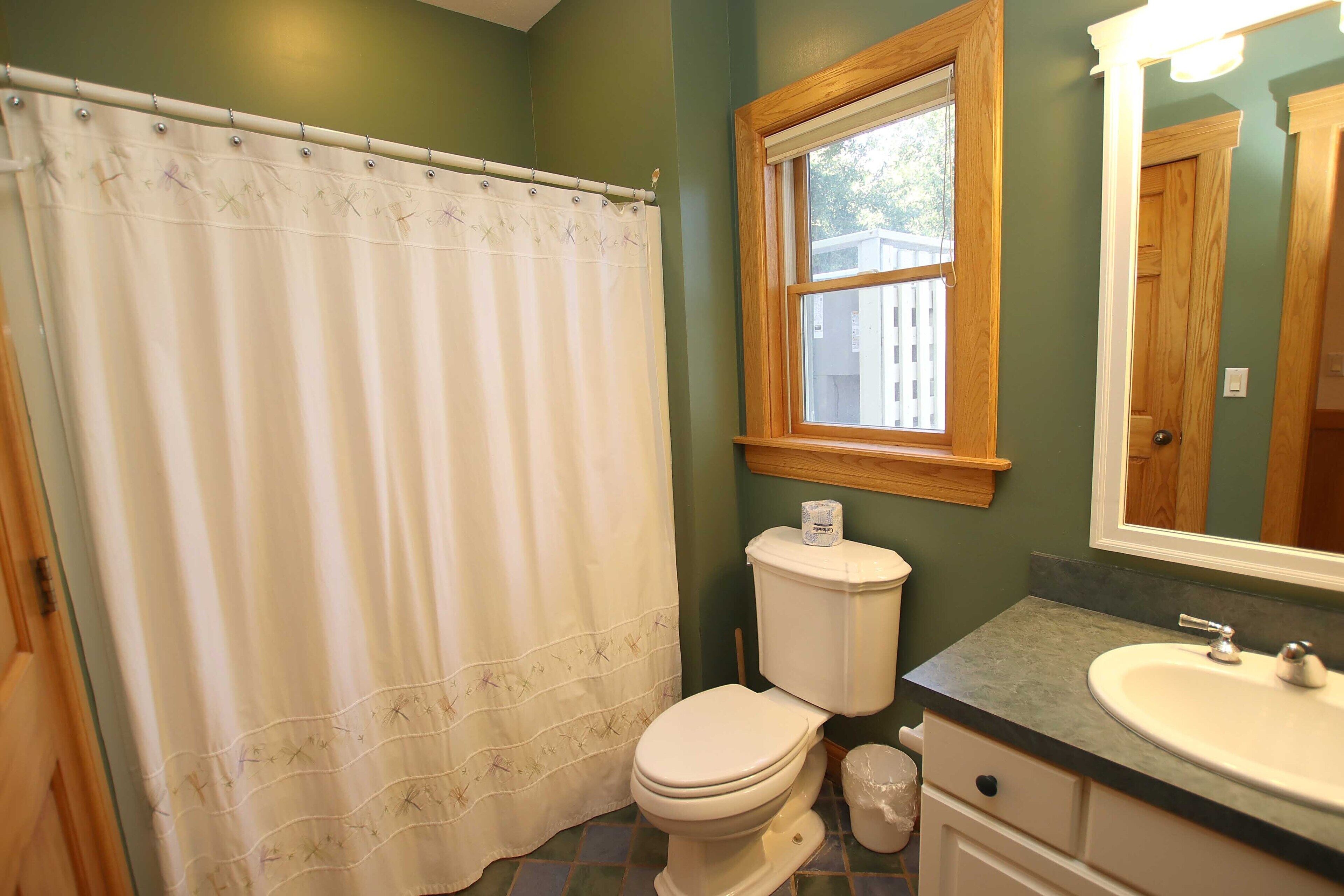 A bathroom with a toilet, sink, and window.