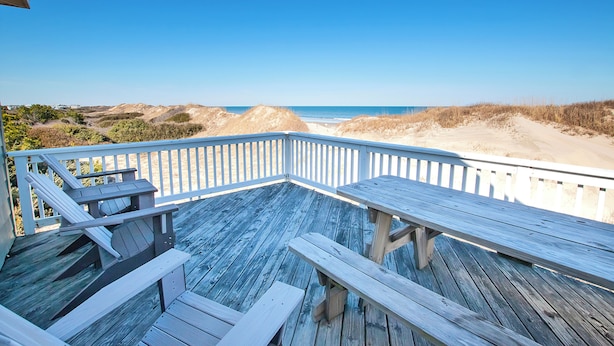 Une terrasse en bois avec des bancs donnant sur une plage.