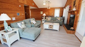A cozy cabin-style room with a sofa, a coffee table, and a fireplace. - Oceanside, Private Pool, Sun Deck, Hot Tub, OS3N, The Lone Star Fish (Corolla)