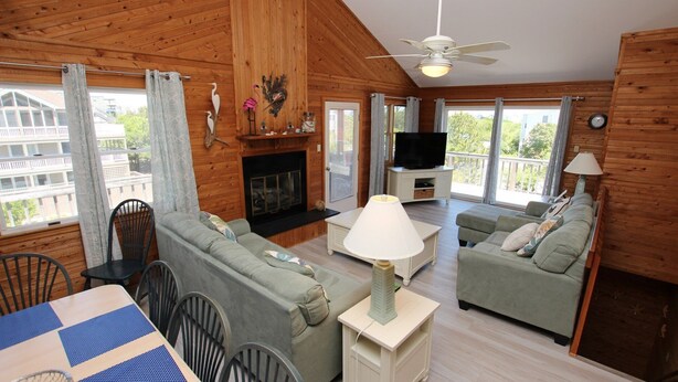 A cozy cabin interior with a fireplace, a television, and a balcony with a view. - Oceanside, Private Pool, Sun Deck, Hot Tub, OS3N, The Lone Star Fish (Corolla)