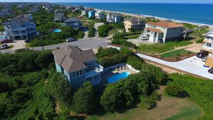 Un quartier résidentiel avec des maisons, une piscine et une plage en arrière-plan.