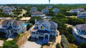 A coastal residential area with multiple two-story houses featuring large balconies and a prominent water tower in the background. - Semi-Oceanfront, Close to Beach, Private Pool, Rec Room, PI13, Ocean's 13 (Corolla)