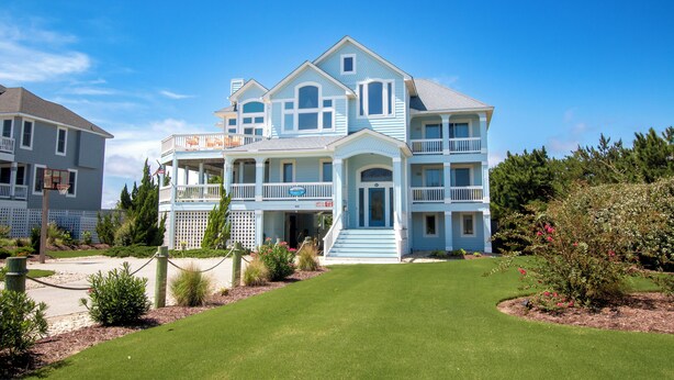 A large, two-story house with a front porch, a covered entryway, and a well-maintained lawn. - Semi-Oceanfront, Close to Beach, Private Pool, Rec Room, PI13, Ocean's 13 (Corolla)