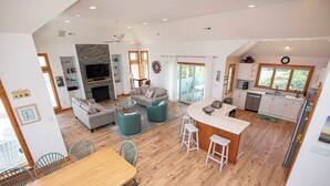 A spacious living area with a fireplace, a sofa, and a dining table with chairs. - Semi-Oceanfront, Close to Beach, Private Pool, Rec Room, PI13, Ocean's 13 (Corolla)