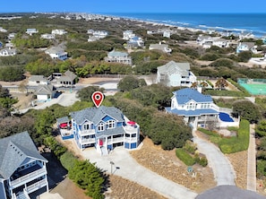 Una zona residenziale costiera con diverse case, un segnaposto rosso ben visibile e vista sull'oceano.