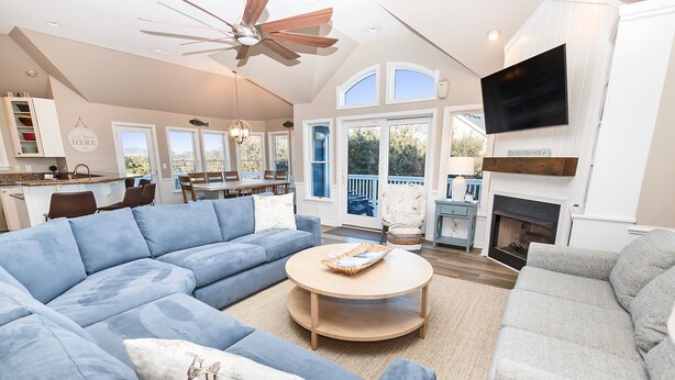 A spacious living room with a sectional sofa, a round coffee table, and a fireplace.