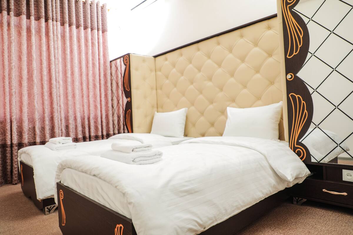 Una habitación de hotel con una cama grande, una cama más pequeña y una mesita de noche.