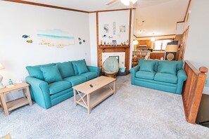 A living room with two teal sofas, a wooden coffee table, and a fireplace. - Oceanside, Close to Beach Access, Community Pool, Ocean Views, KHSDC2, Sea Dunes C2 (Kitty Hawk)