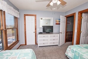 A bedroom with two beds, a dresser, a television, and a ceiling fan. - Oceanside, Close to Beach Access, Community Pool, Ocean Views, KHSDC2, Sea Dunes C2 (Kitty Hawk)