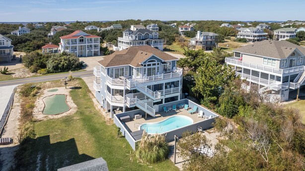 Une vaste propriété en bord de mer, comprenant plusieurs étages, une piscine, de nombreux balcons et une vue sur l’océan.