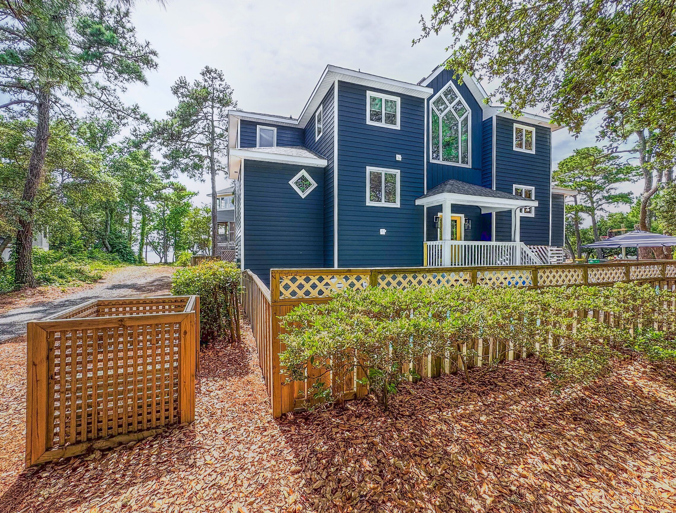 A two-story house with a dark blue exterior, a covered porch, and a wooden fence.