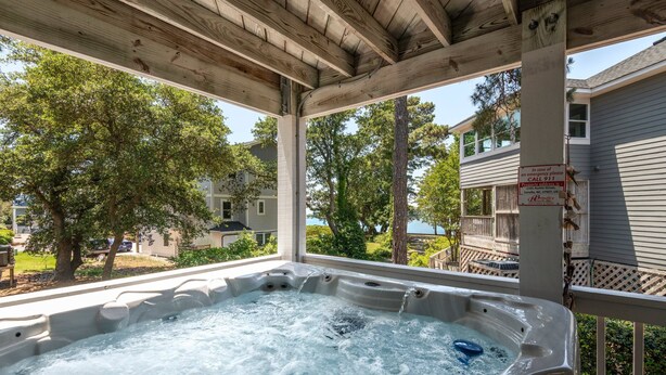 Jacuzzi sota una pèrgola de fusta amb vista a un barri residencial.