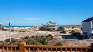 A beachfront property with a large house featuring multiple balconies and a covered porch, surrounded by sandy dunes and sparse vegetation. - Semi-Oceanfront, Pets Welcome, Wild Horses, Ocean Views! 4x1678, Turtle Trax (Corolla)