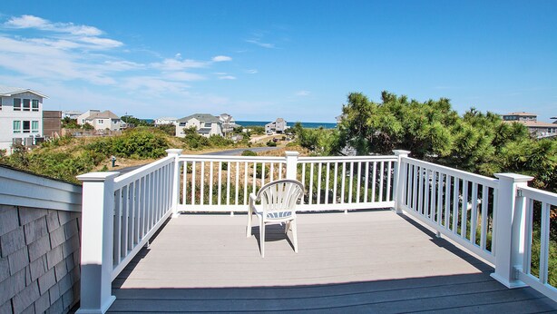 A wooden deck with a white railing, a single chair, and a view of houses and the ocean. - Oceanside, Priv Pool, poolside grilling, sun decks, SEA6, Morningstar (Duck)